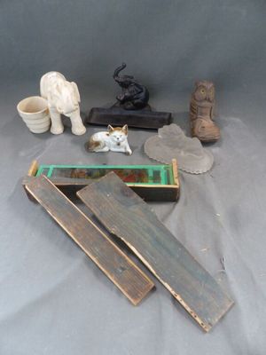 Plusieurs morceaux de bois sont posés sur une table, à côté desquels se trouve une figurine de chat.