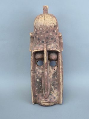un gros plan d'un masque en bois sur fond bleu