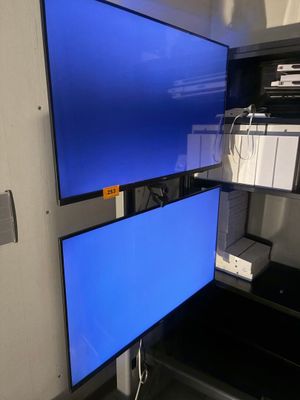 deux écrans d'ordinateur posés sur un bureau dans une pièce