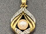 a gold and white pearl pendant on a gray surface