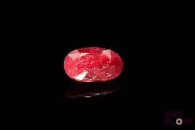 a close up of a red ruby stone on a black surface