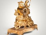 a gold clock on a stand with a clock on top of it