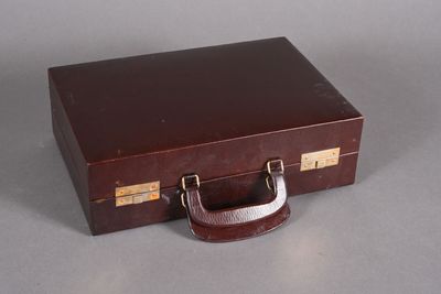 une valise marron posée sur une table, avec une poignée