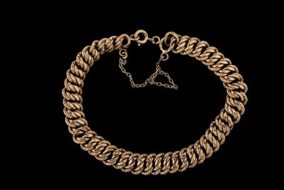 gros plan d'un bracelet en or sur fond noir