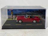 a red toy car in a clear box on a white surface
