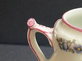 a small white vase with a pink handle on a table