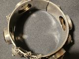 an antique silver bracelet on a gray cloth with a silver clasp