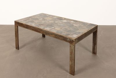 une photo d'une table basse avec un plateau en carrelage posée sur un sol en béton