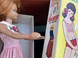 a doll that is standing next to a box with a doll in it