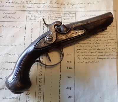 un vieux pistolet posé sur une feuille de papier, sur une table