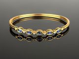 a gold bangle with blue and white stones
