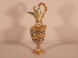 a gold vase with a bird on it on a table