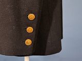 a close up of a black jacket with gold buttons on a mannequin