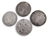 four silver coins of different sizes and shapes on a white surface