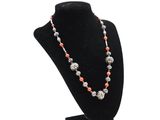 a necklace with coral and silver beads on a black mannequin