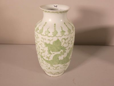un vase blanc orné d'un motif représentant un dragon vert