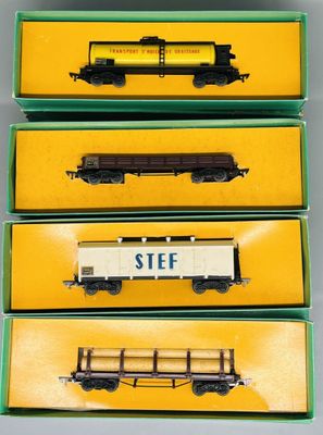 trois trains miniatures dans leurs boîtes, posés sur une table