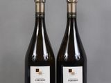two bottles of wine sitting on top of a table next to each other