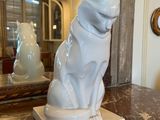 une statue représentant un chat assis sur une table en marbre