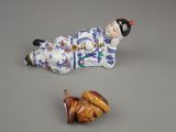 a figurine of a woman laying on the ground next to a plate of food