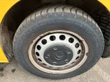 a yellow bus with a flat tire parked on the street