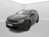 Une voiture noire est garée dans une pièce blanche au sol blanc.