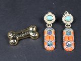deux paires de boucles d'oreilles et un os pour chien posés sur une surface noire