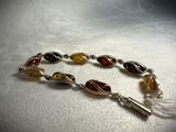 silver and amber beaded bracelet with a tassel charm
