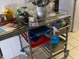 chariot de cuisine en acier inoxydable sur lequel sont posés des ustensiles, dans une cuisine