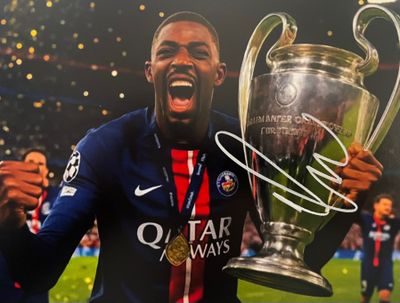 Le footballeur tient un trophée dans ses mains.