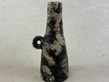 un vase noir et blanc posé sur une surface blanche