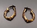 pair of gold bamboo hoop earrings on a gray surface