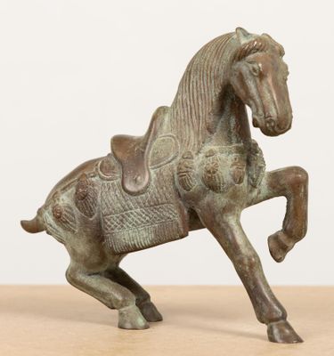 statue en bronze représentant un cheval avec une selle posée sur ses pattes arrière