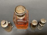 a small glass bottle with a silver lid next to salt and pepper shakers