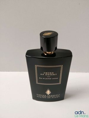 a close up of a bottle of perfume on a white surface