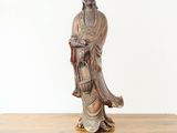 statue of a woman holding a basket on top of a wooden table