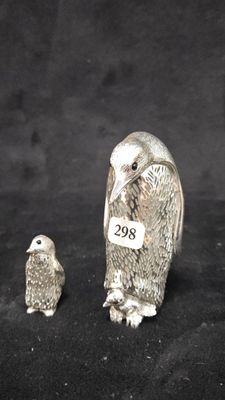 two silver figurines of birds on a black background