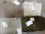 quatre paires de pulls et un sac à main sont posés sur un canapé