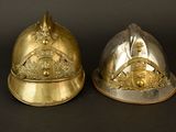 pair of brass helmets with crest and shield on top of each other