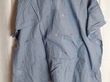 shirt hanging on a hanger on a bed with a white sheet in the background