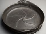 une assiette noire sur laquelle est représenté un oiseau, posée sur une table