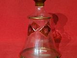 une bouteille en verre avec un bouchon doré sur fond rouge