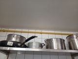 pots and pans are lined up on a shelf in a kitchen