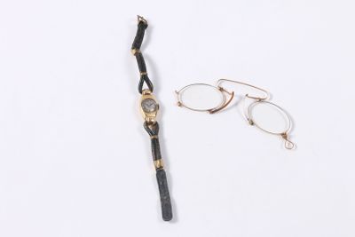 pair of glasses and a watch laying on a white surface