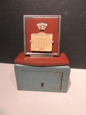 une petite horloge posée sur une boîte, elle-même posée sur une table