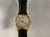 a small gold watch on a black leather strap