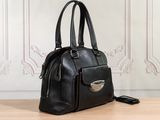 black leather handbag sitting on a wooden table with a cell phone in front of it