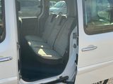 une camionnette blanche dont la porte est ouverte, garée sur le bord de la route