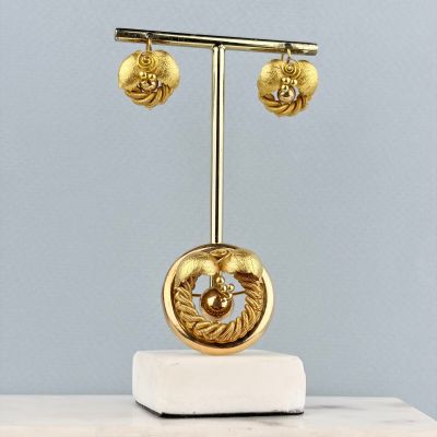 une sculpture en or posée sur un socle en marbre, elle-même posé sur une table