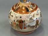 a vase with a painting on it sitting on a table